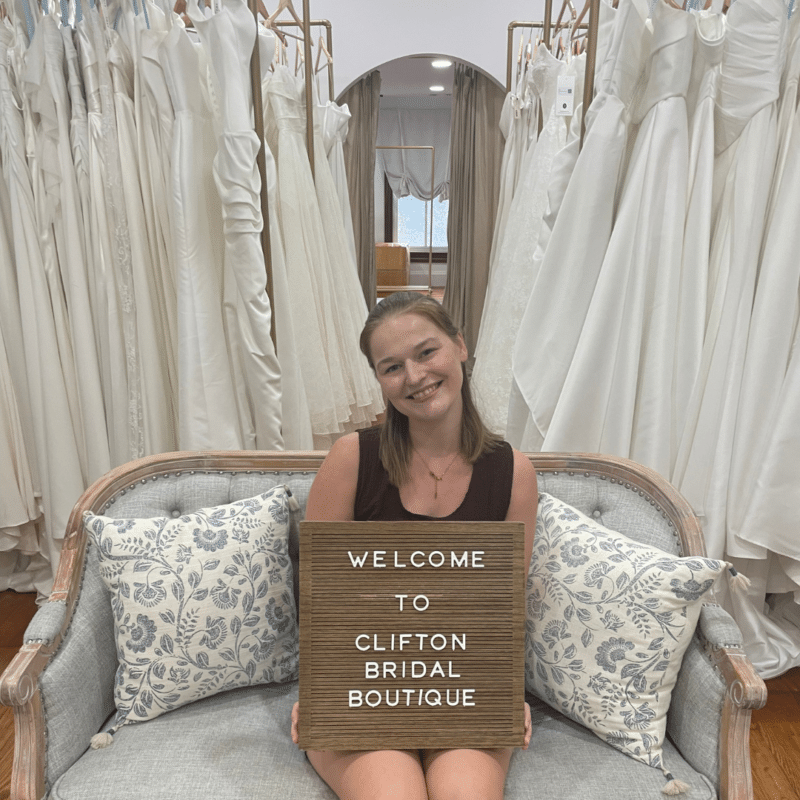 Katie, owner of Clifton Bridal, sits with a sign 