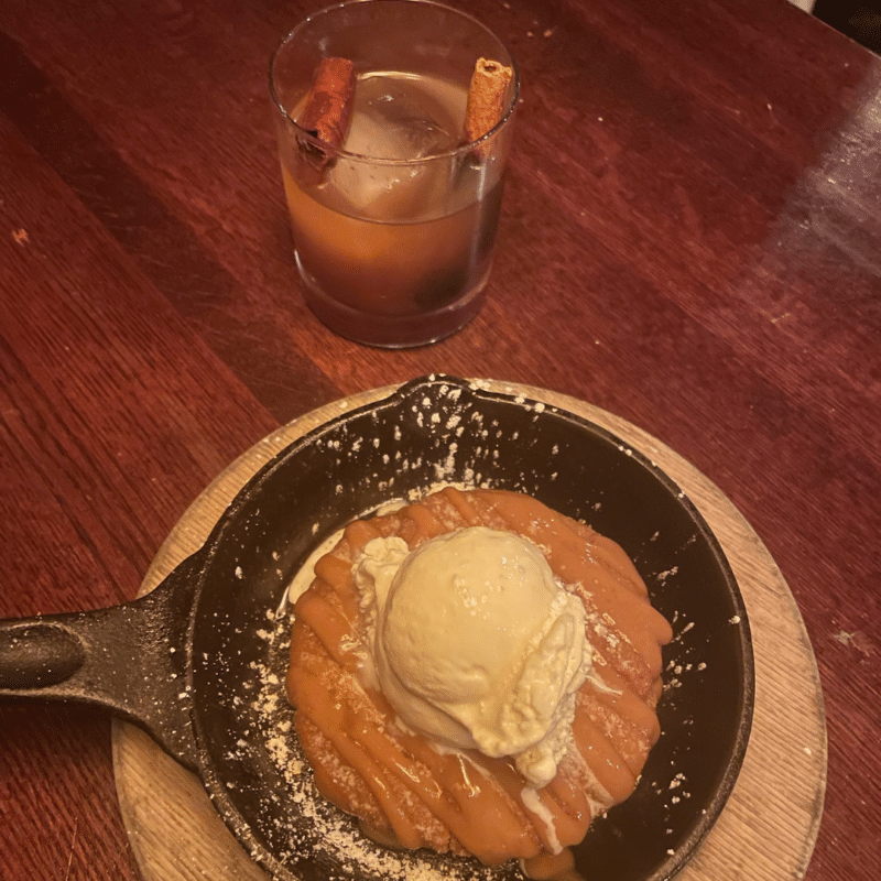 Skillet dessert with vanilla ice cream on top and a cocktail